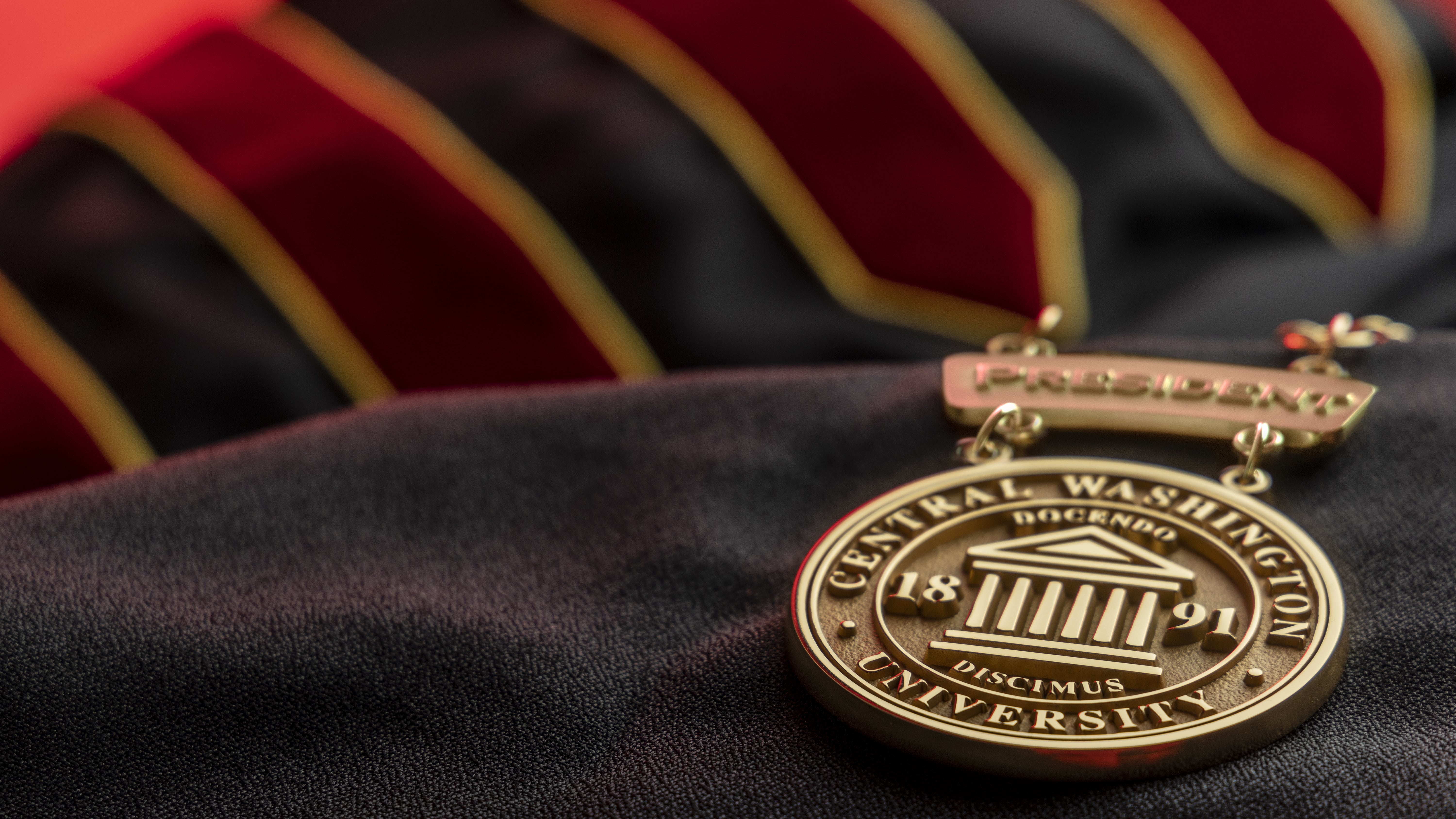 CWU Medallion laying on top of black regalia.