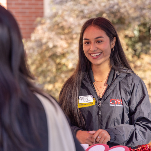 Student helping another student outside during an admissions event.