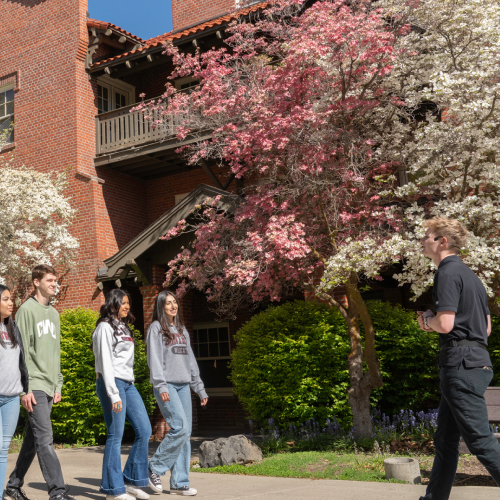 Students on a tour during spring while the lilac bushes are fully bloomed.