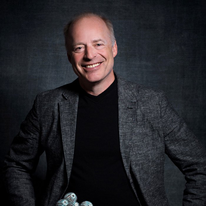 Formal portrait of Professor Mark Goodenberger sporting a gray jacket over a black sweater.
