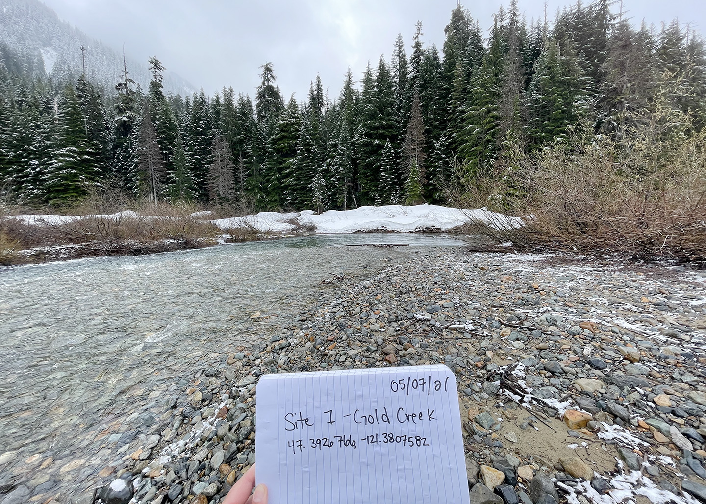 J Shah holds up a notebook along the Yakima River
