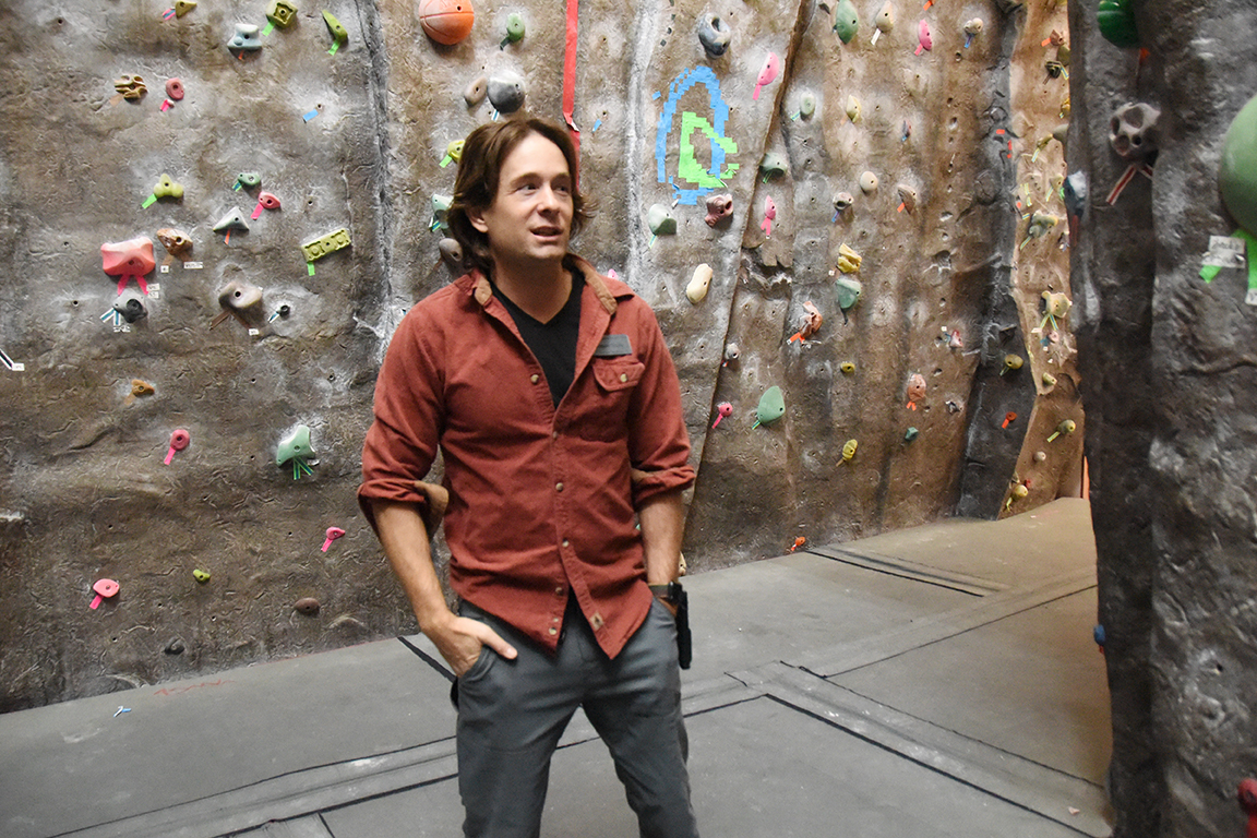 Logan Scully stands at the base of the CWU climbing wall in the SURC.