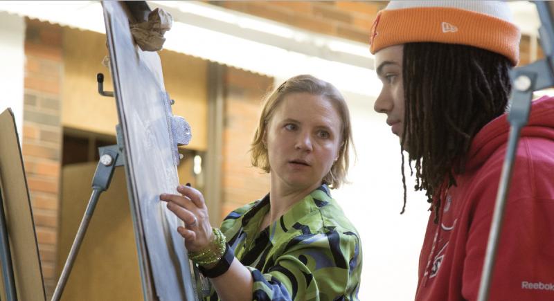 Faculty member Rachel Kirk helping explain a drawing method to a student.