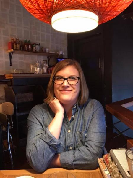 Seanse Ducken grinning at camera in restaurant wearing a blue button up shirt and frames.