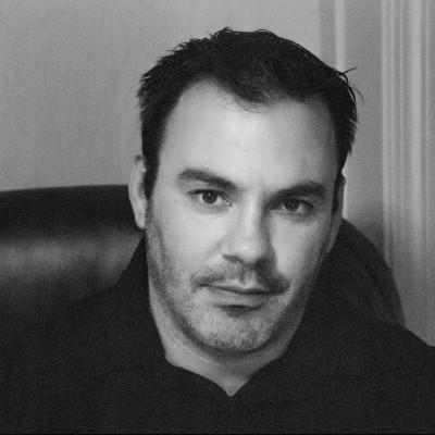 Jeff Suwak sitting in a high back chair looking stoic in black and white