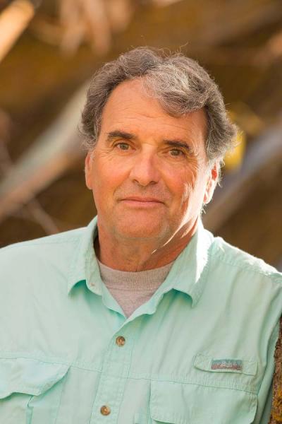 Joe Powell grinning at the camera in a mint button down shirt