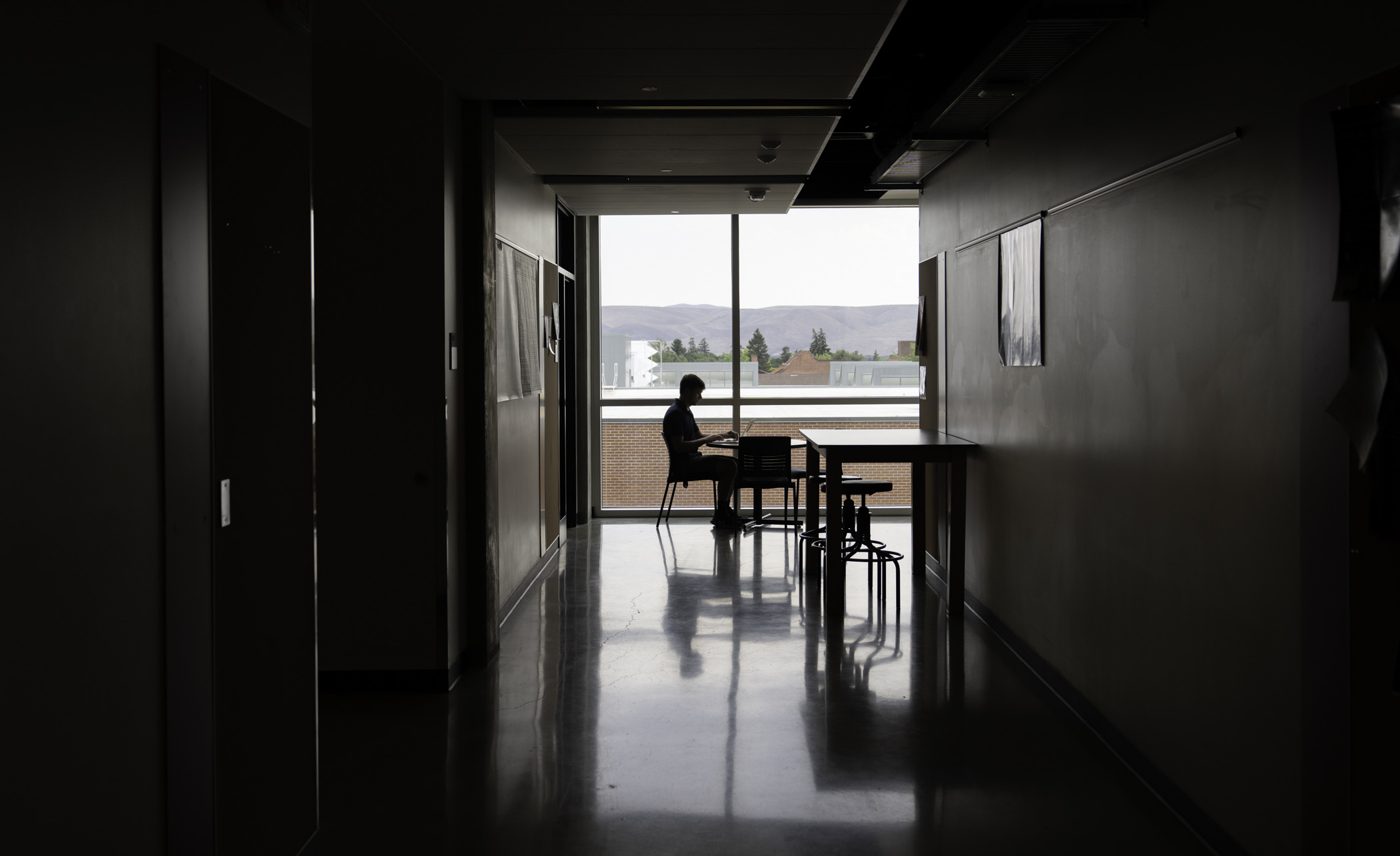 Student studying at the end of a long hallway.