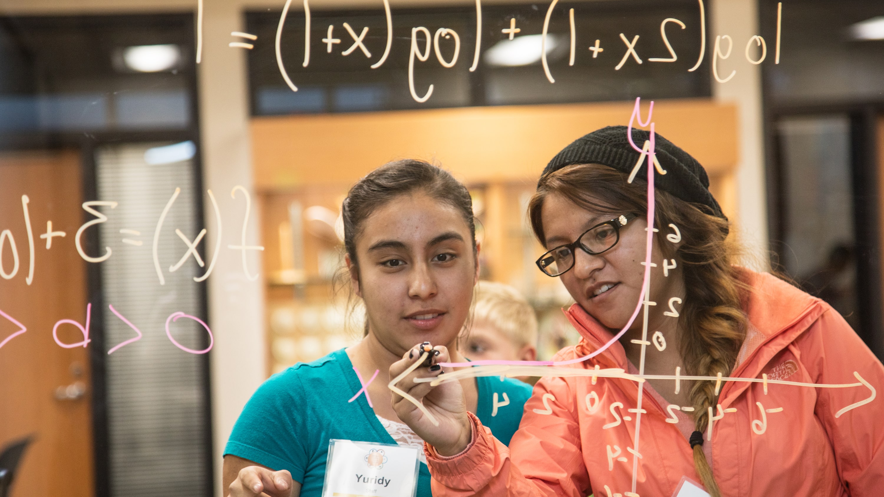 Students doing a math assignment on a see-through whiteboard