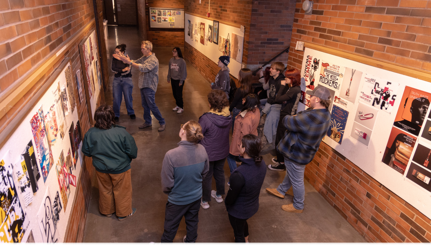 Students and professors reviewing art in the hallway