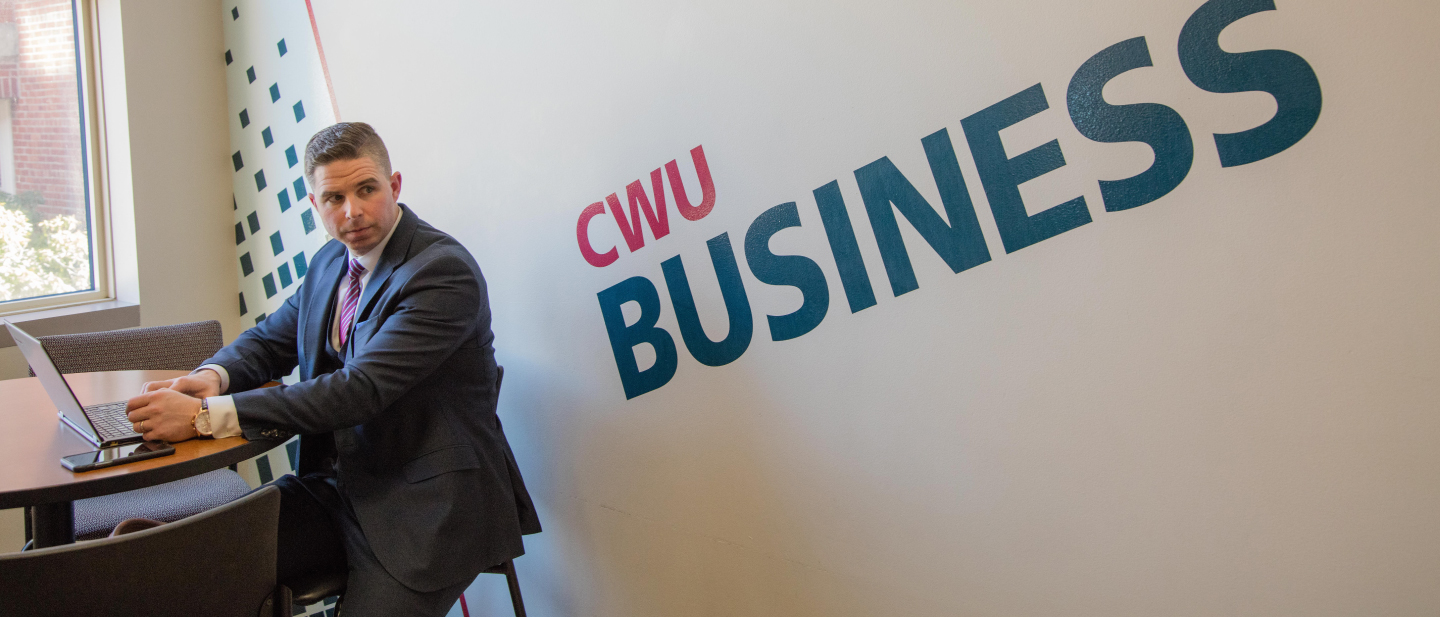 Student in a suit working on his laptop.