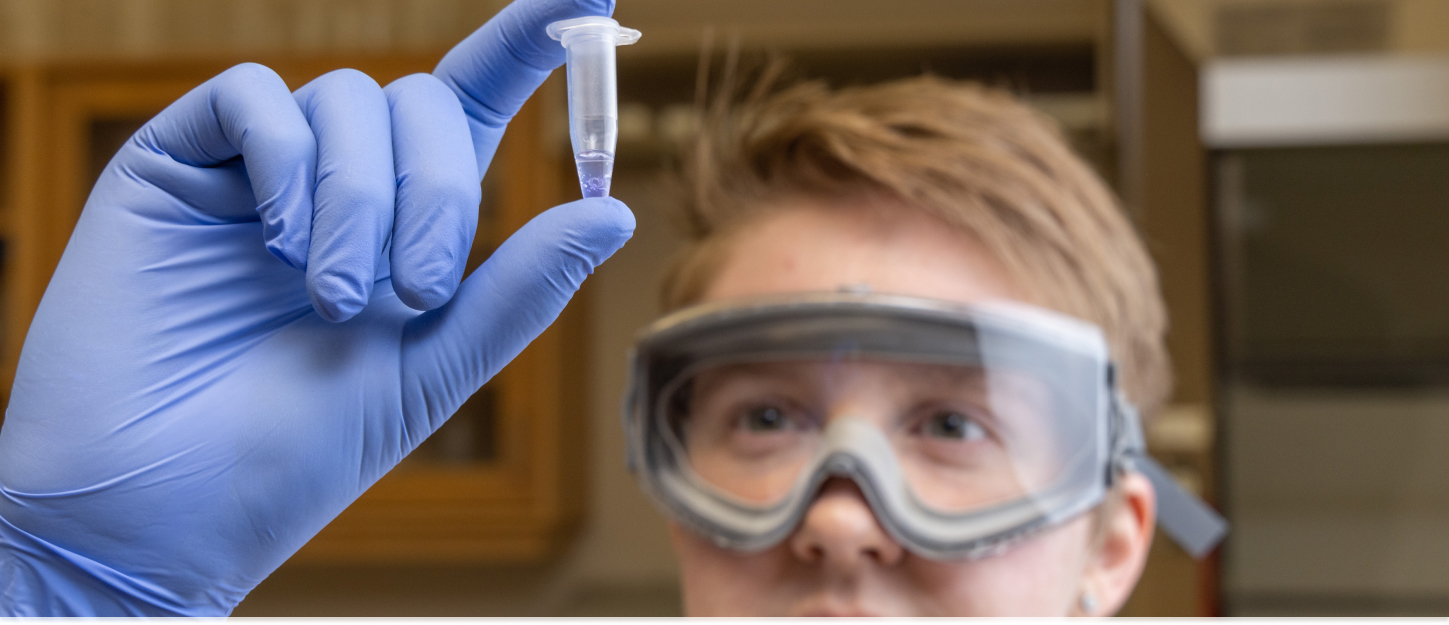 Student holding up a tiny dropper with liquid in it during a lab