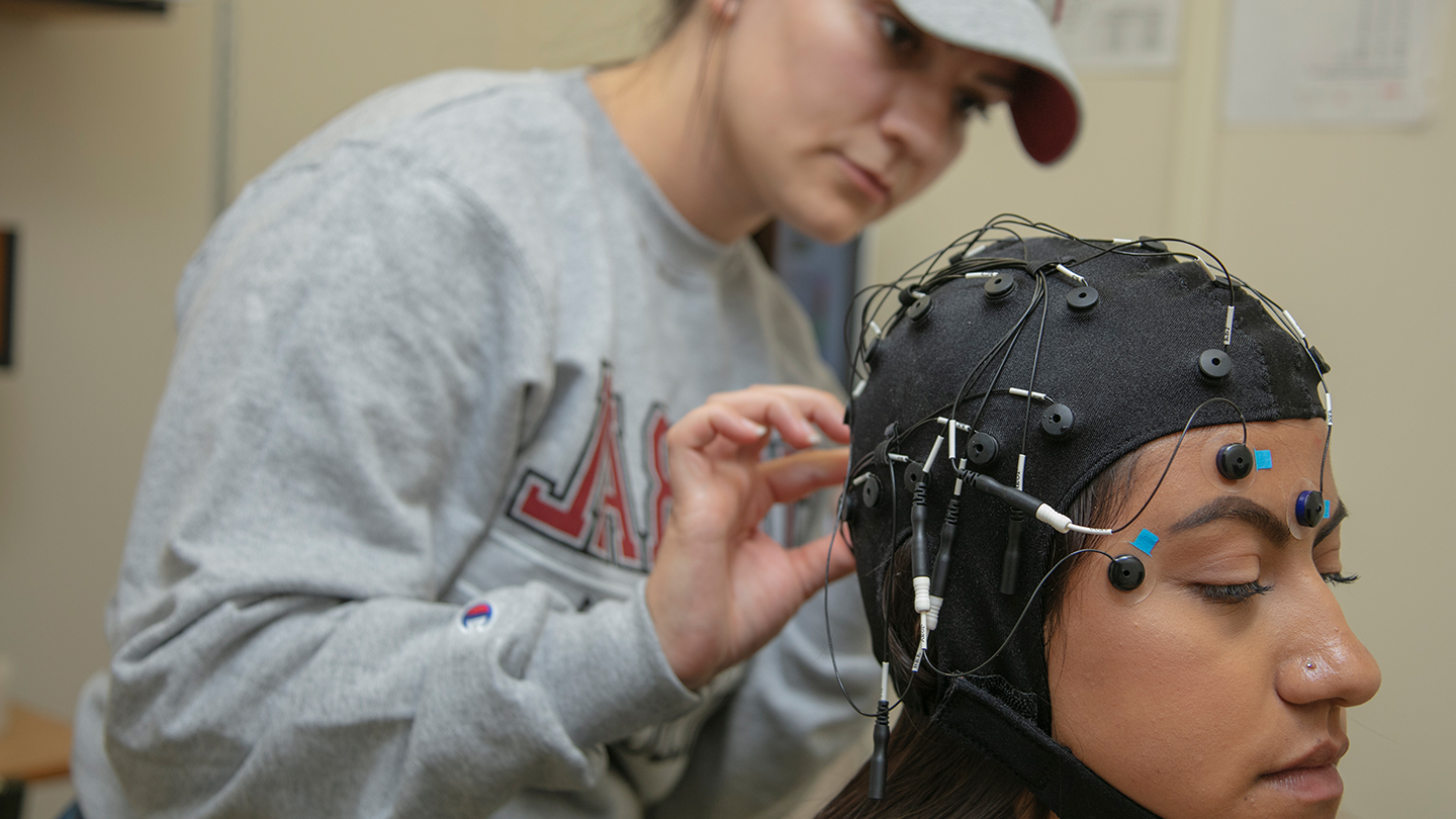 Student is adjusting device on a student’s head during a lab