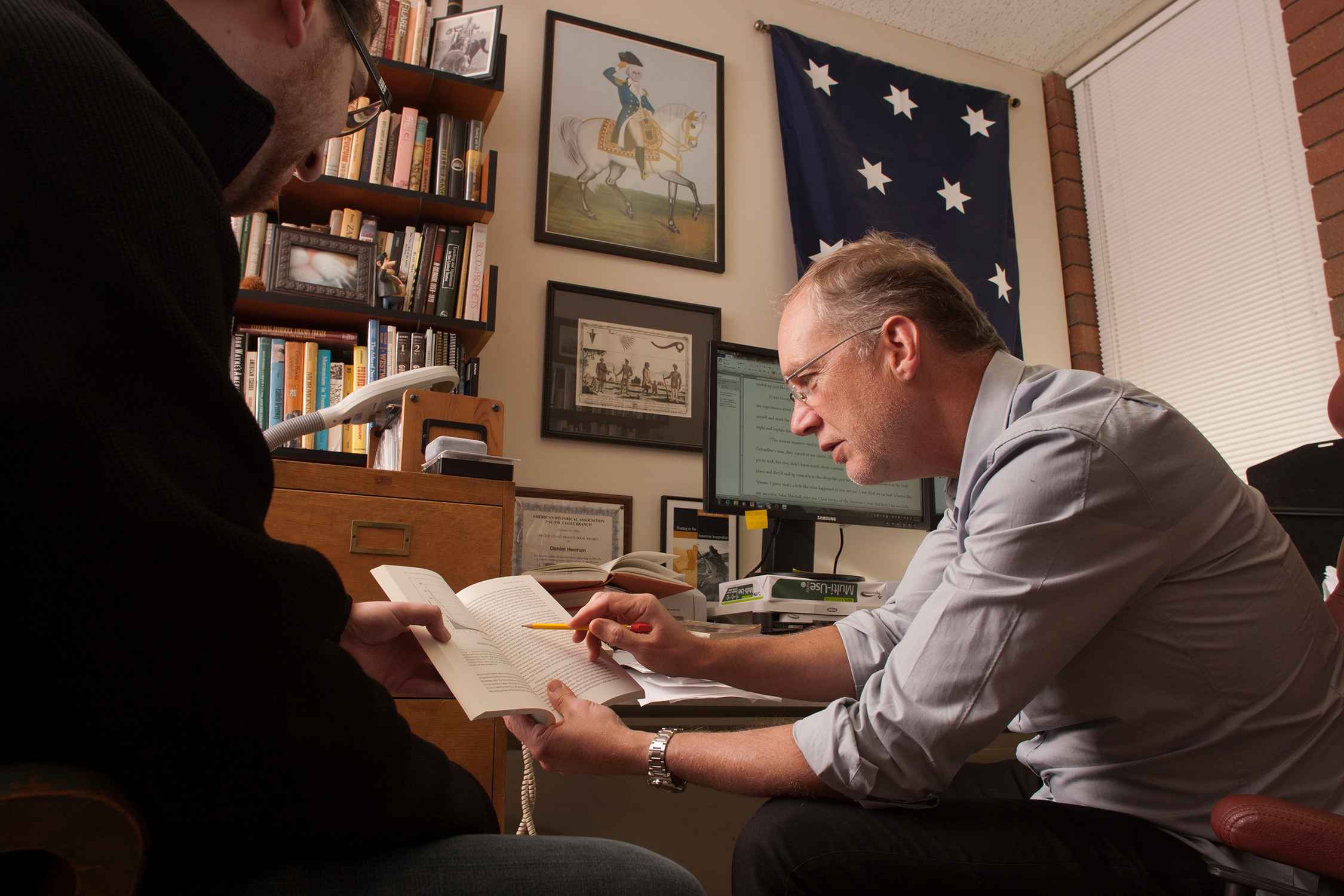 Professor and student reading a book together