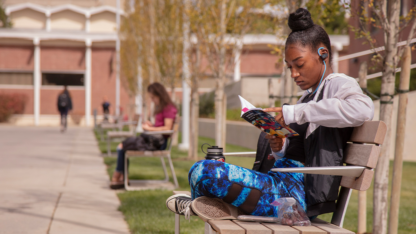 Student sitting on a bench reading a book