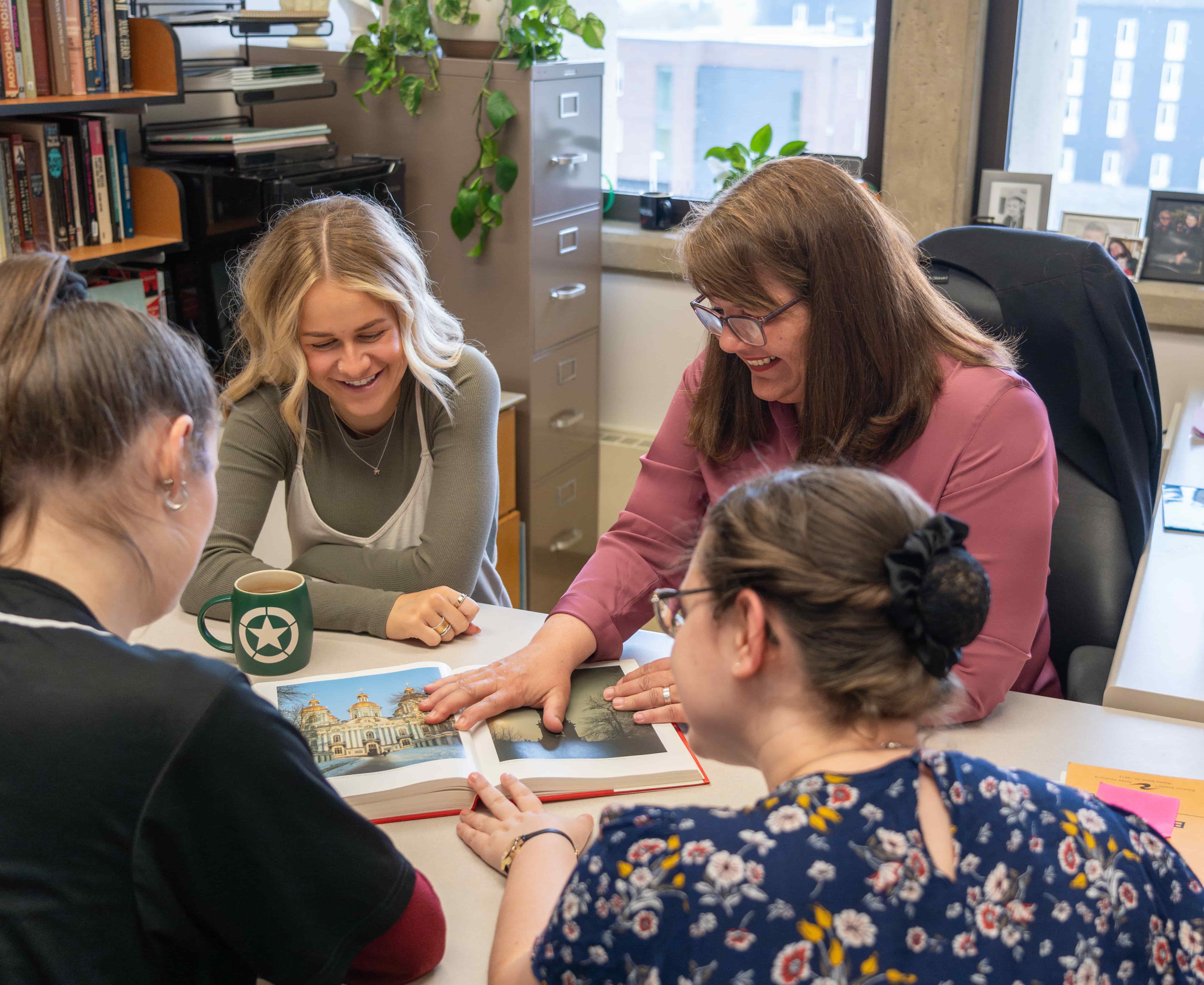 Three students and a professor looking through an architectural book.