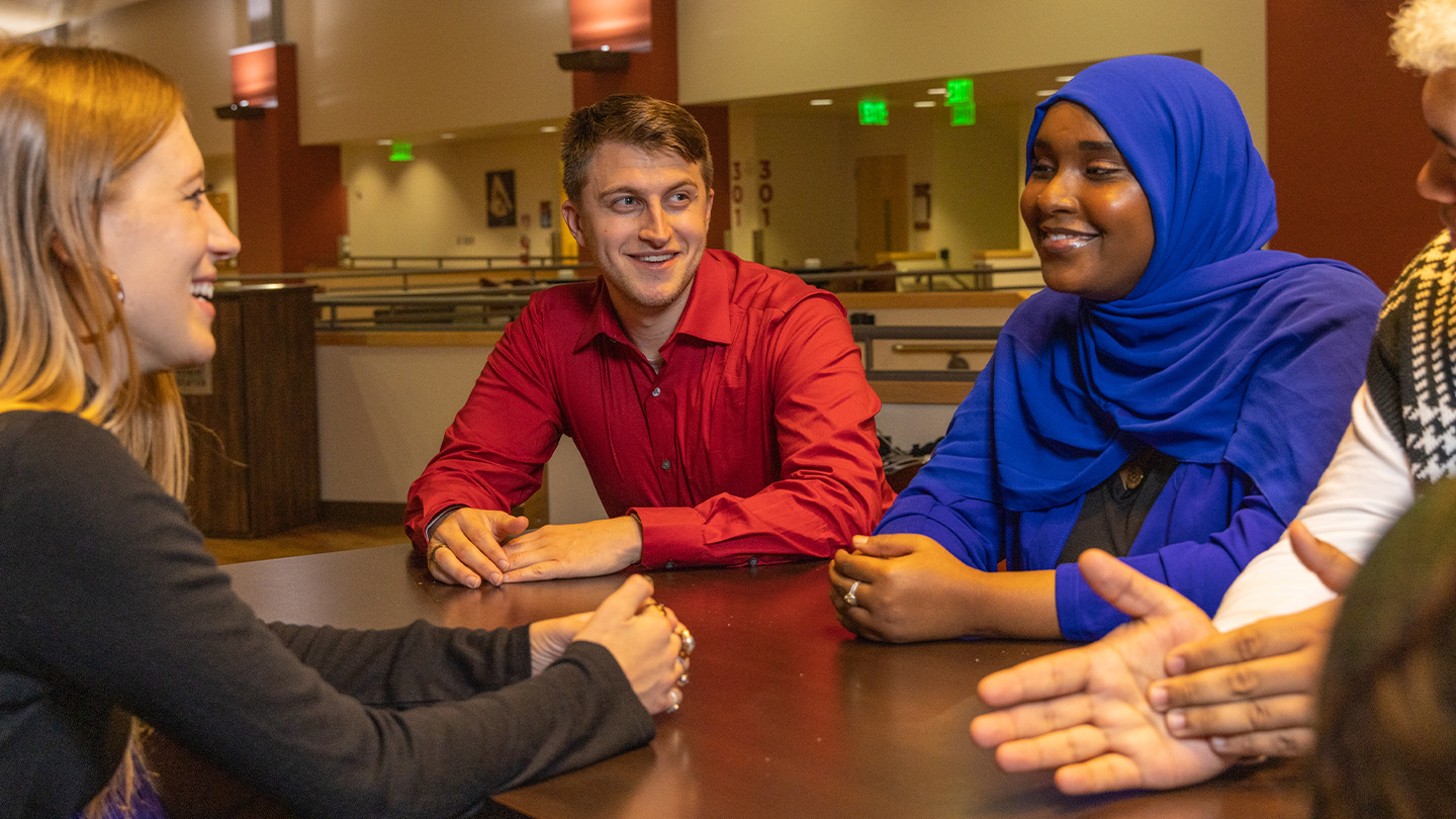 Students sitting around a table talking.