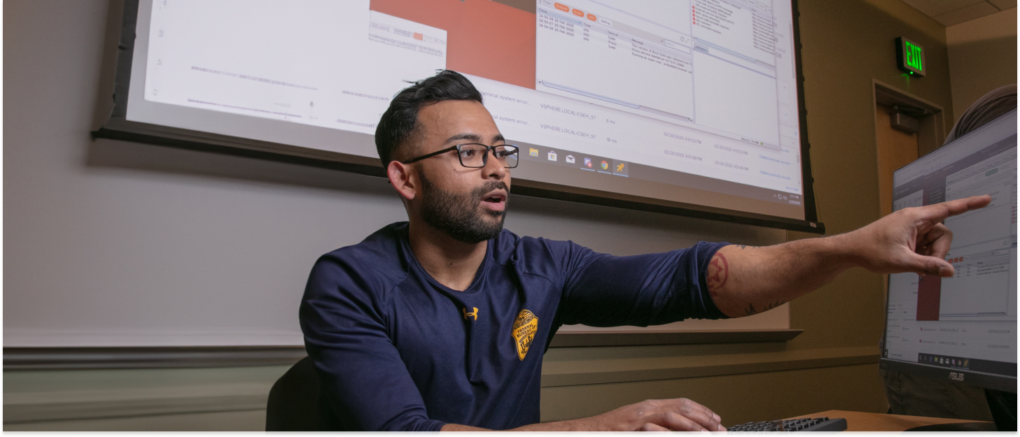 Student pointing towards something on the computer screen.