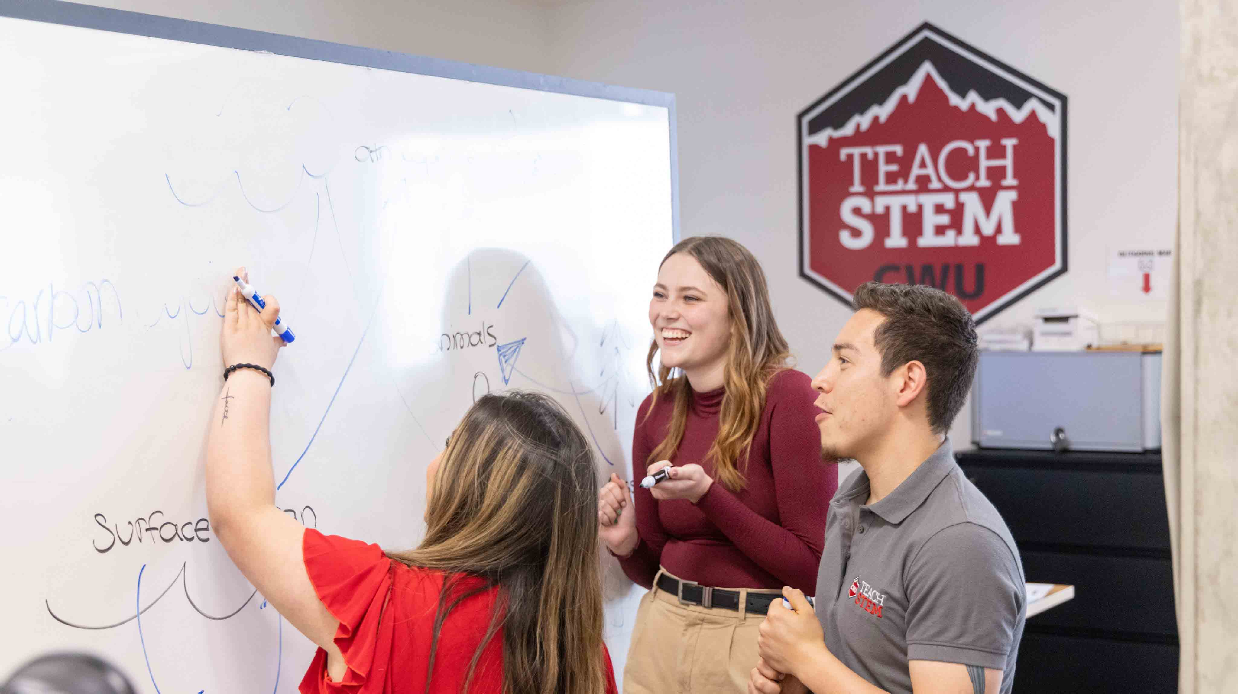 Three students working together on a whiteboard