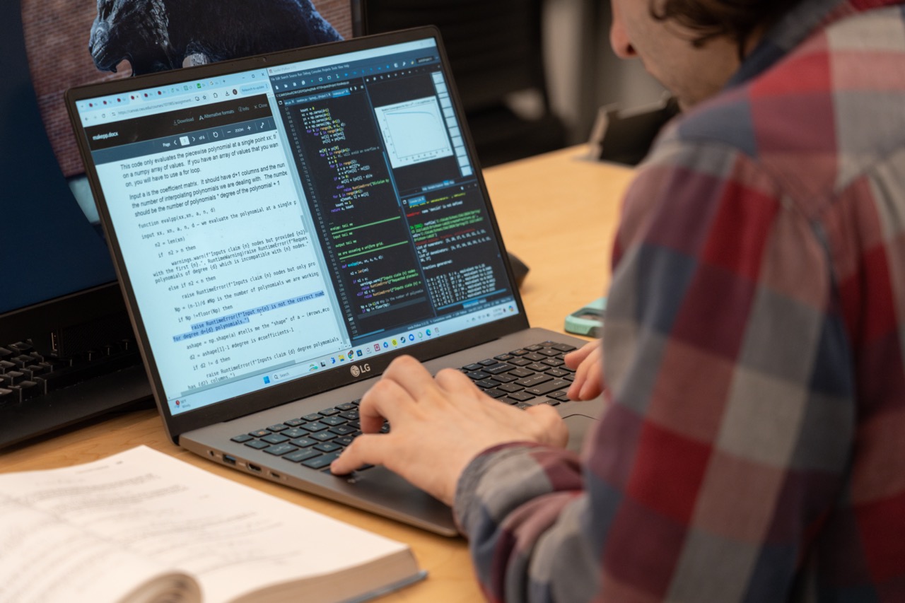 Student typing and coding on a laptop.