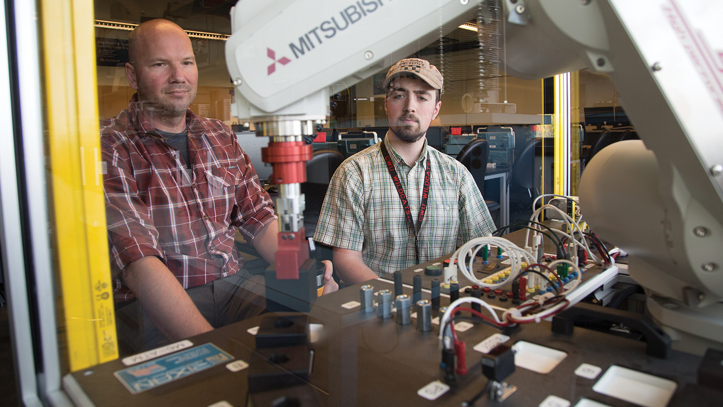 professor and student operating motorized arm