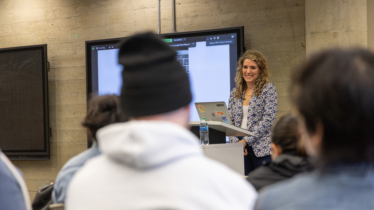 Professor giving a lecture in front of a screen.