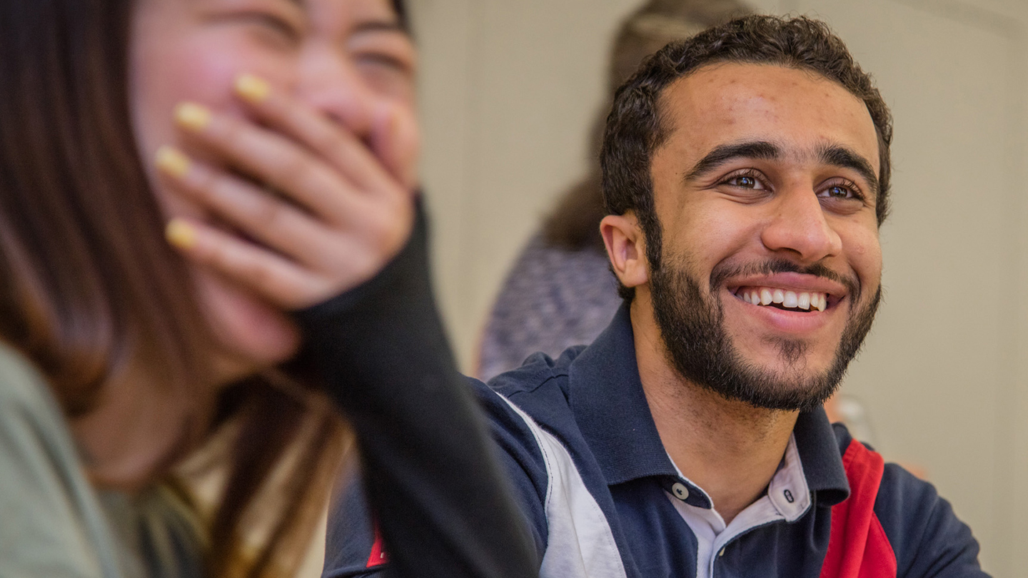 Student smiling with another student laughing next to them.