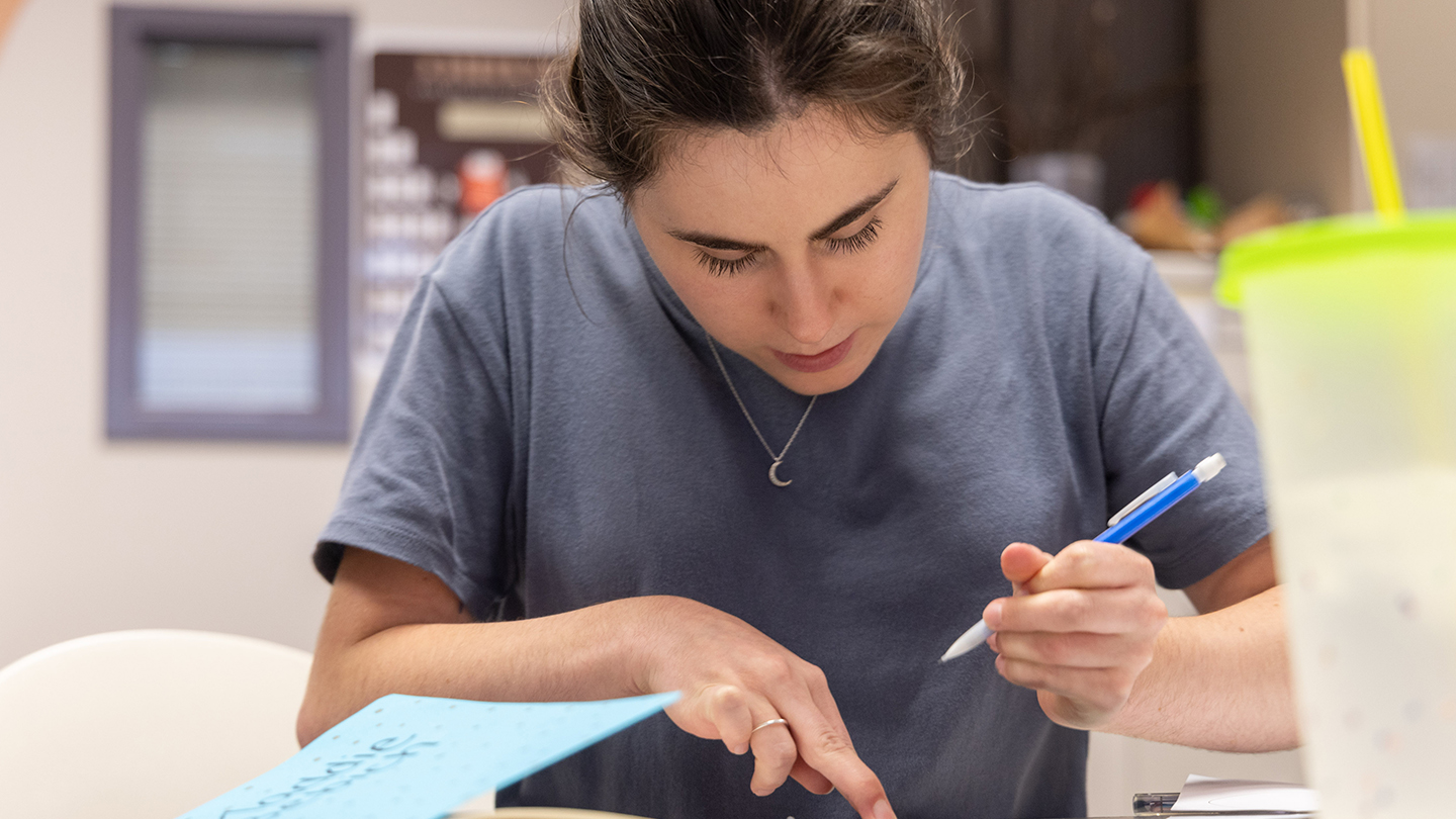 Student writing at a desk. 
