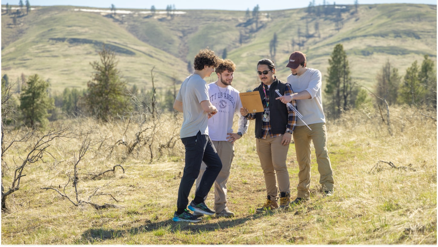 Three students working with a professor on a project outside in the Kittitas Valley