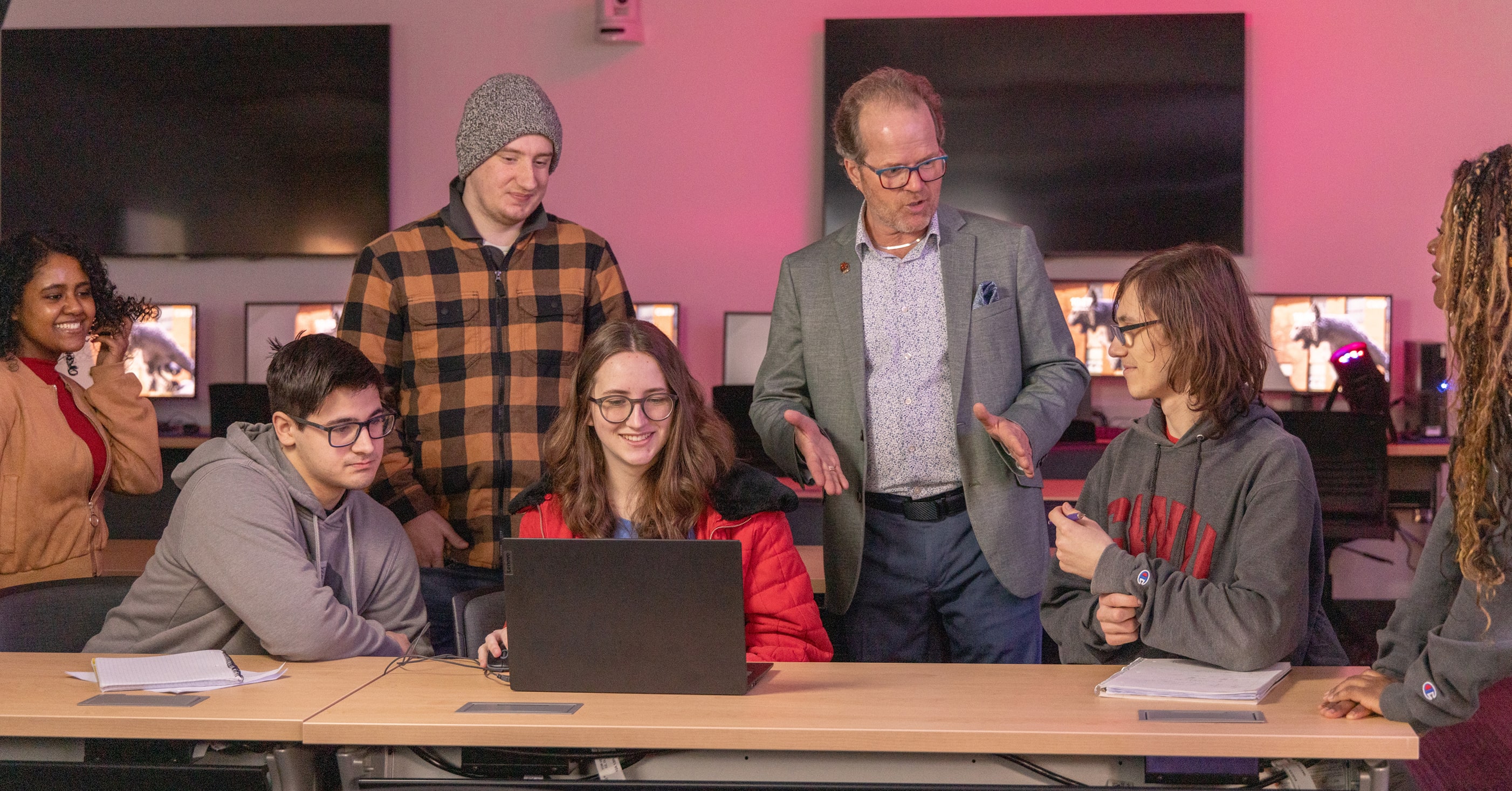 Professor explaining something on a computer to students
