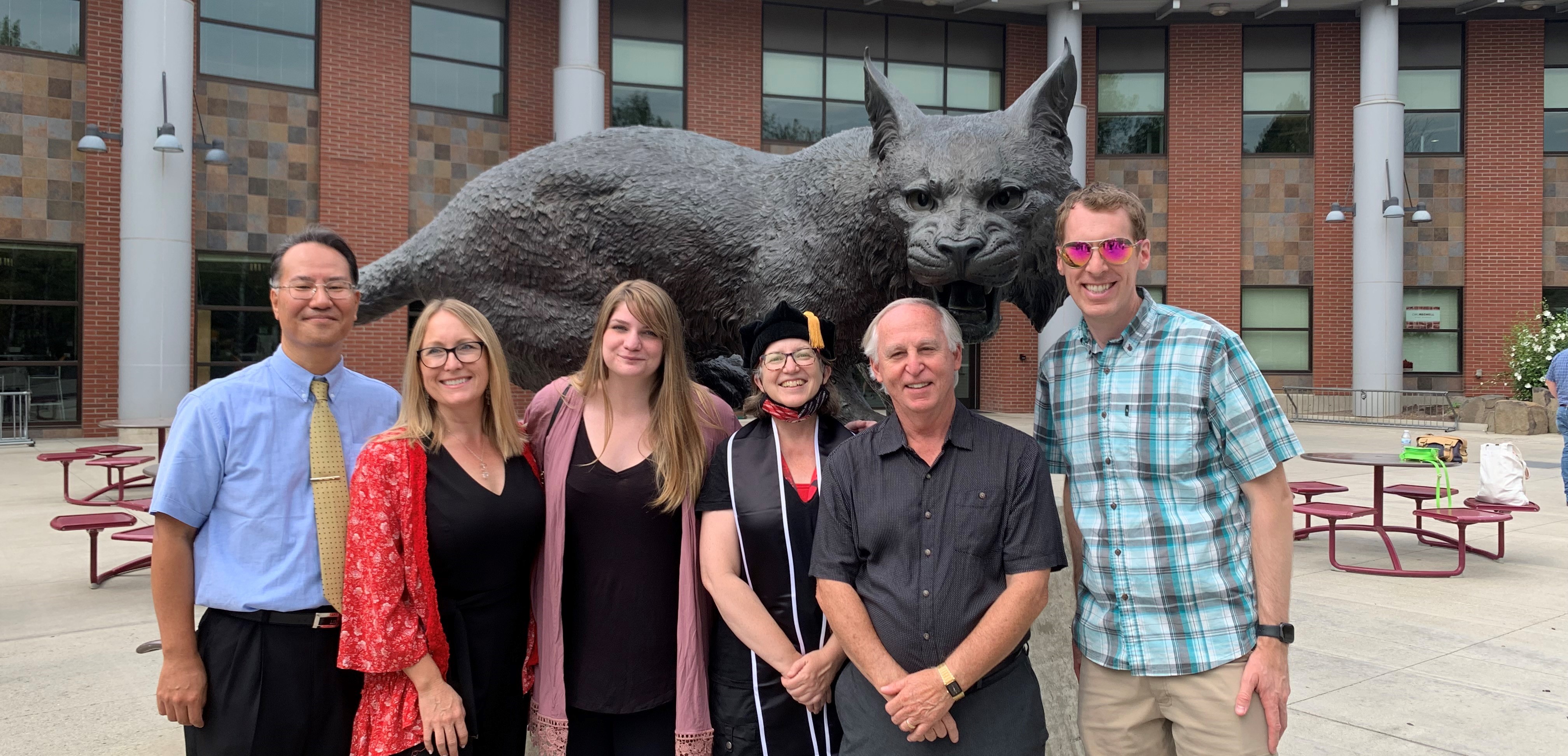 Group photo of the MS ITAM Faculty. They are standing in front of the Wellington the WIldcat statue at the SURC