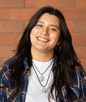 Tiffany Ochoa smiling in a picture. There is a brick wall behind her