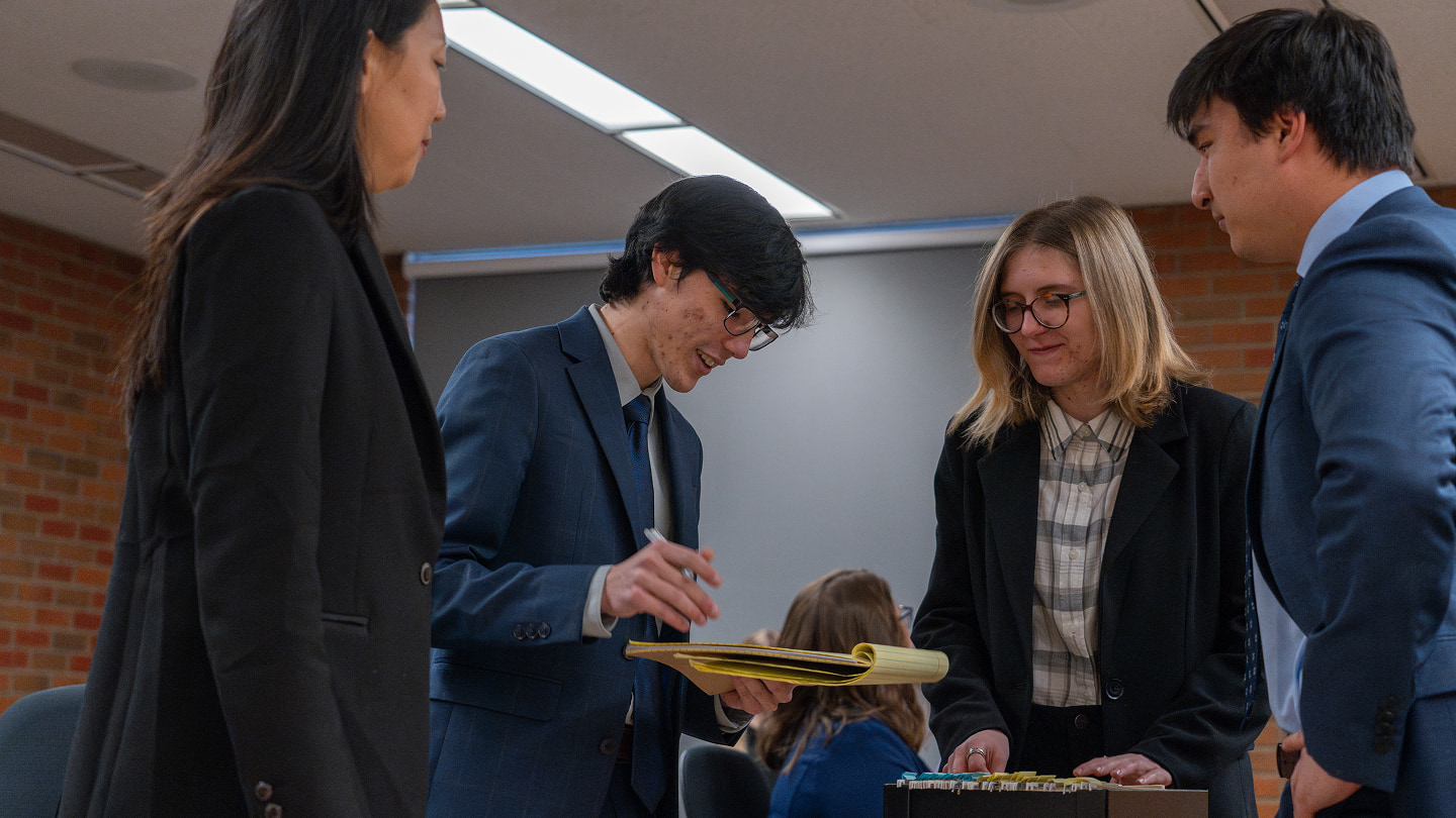 Three students discussing a court case during an interactive class experience.