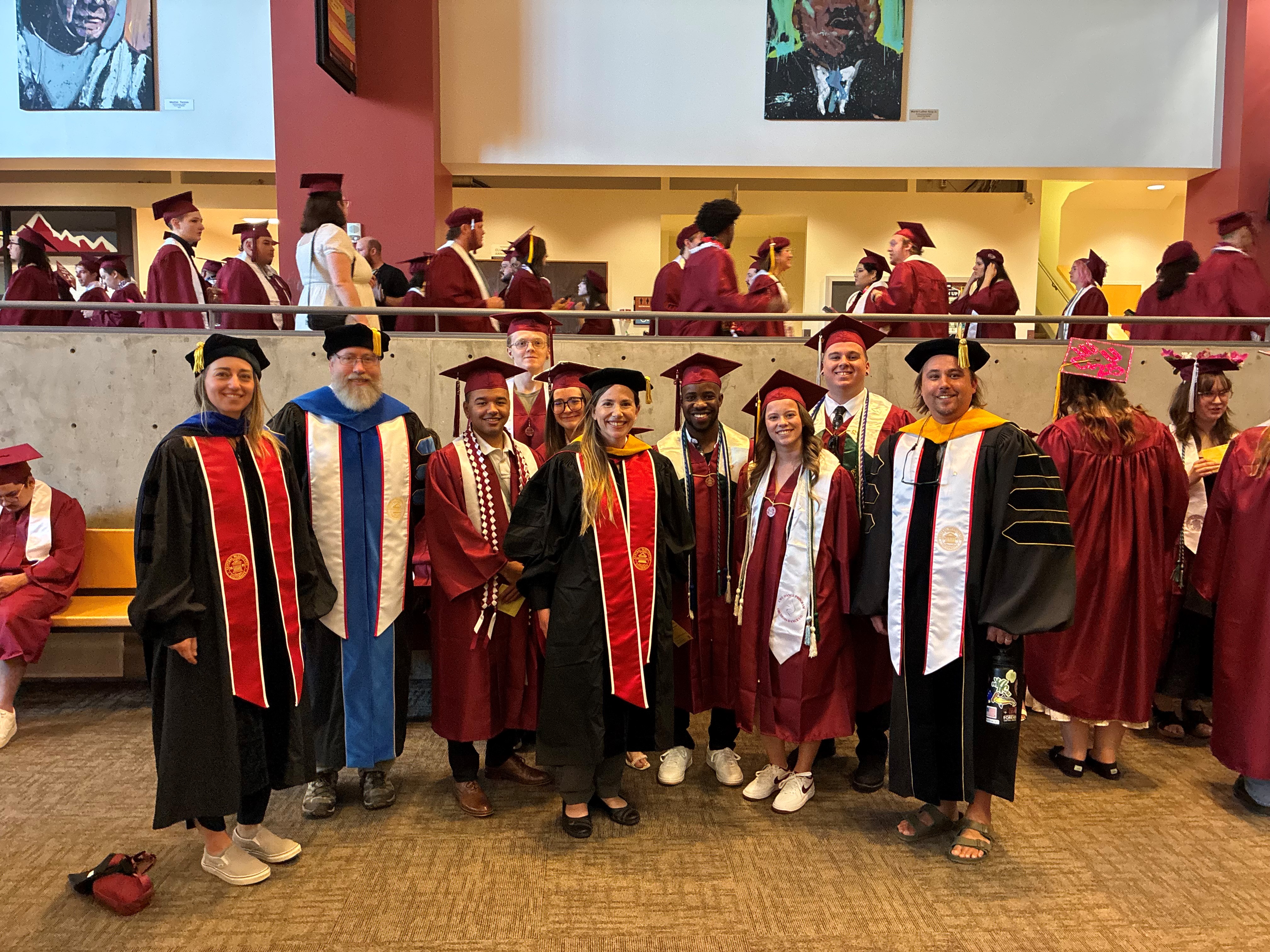 The Physics faculty and graduates all in regalia smiling at graduation