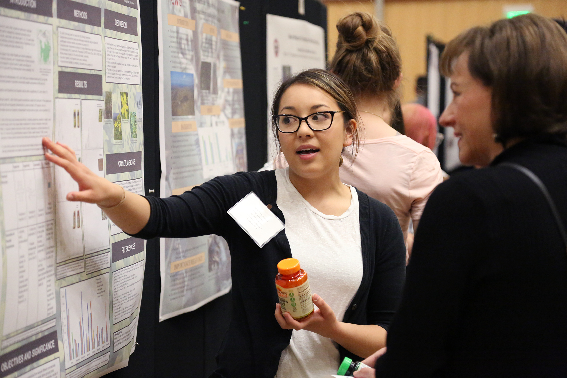 Student presenting research poster to a woman.