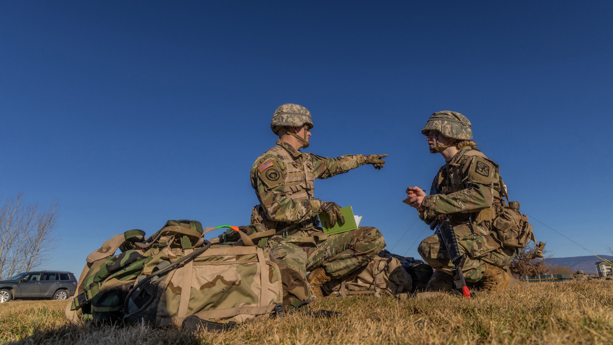 Two army students reading and pointing to something during training.