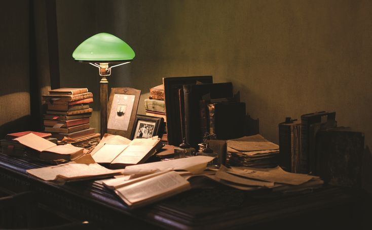 A desk full of books and paper all over the place