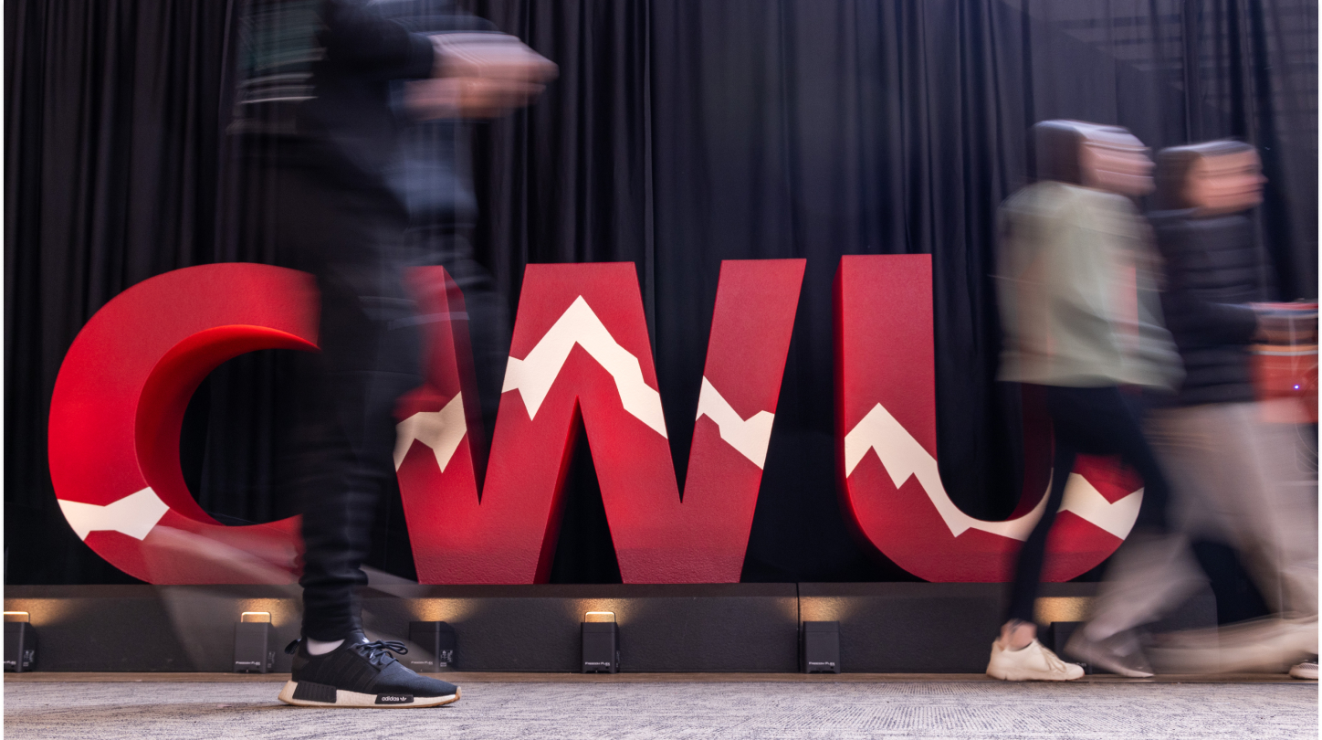 Blurry people walking by large CWU letters