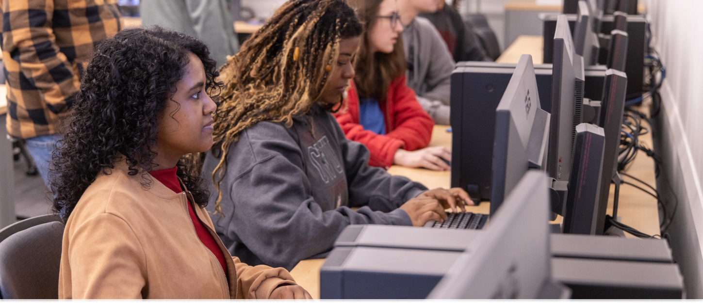 Students working in front of a computer in a group lab.
